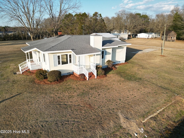 view of front of property featuring crawl space, roof with shingles, a chimney, and a front lawn