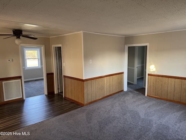 spare room featuring visible vents, carpet flooring, a ceiling fan, and ornamental molding