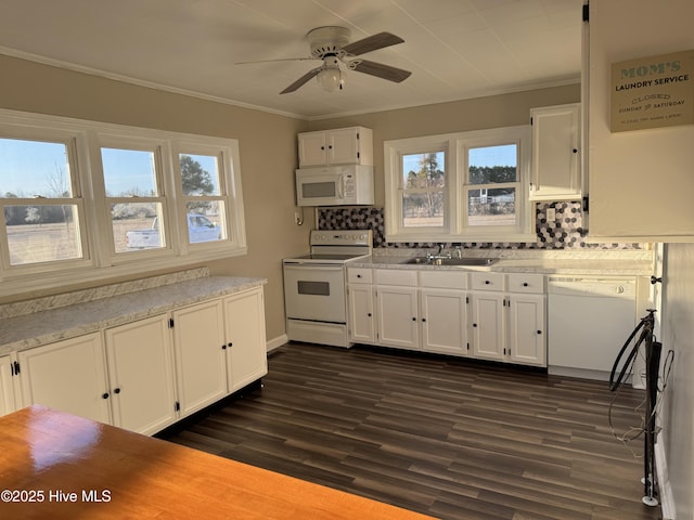 kitchen with ornamental molding, white appliances, white cabinets, and a sink