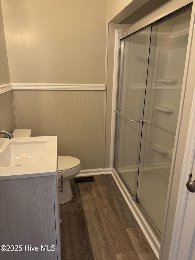 bathroom with wainscoting, visible vents, a shower stall, and wood finished floors