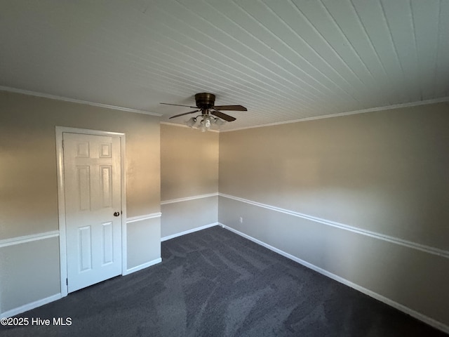 unfurnished room with baseboards, a ceiling fan, dark carpet, and crown molding