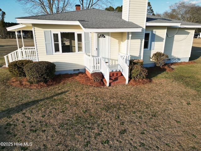 view of front of home featuring crawl space, a front yard, covered porch, and a chimney