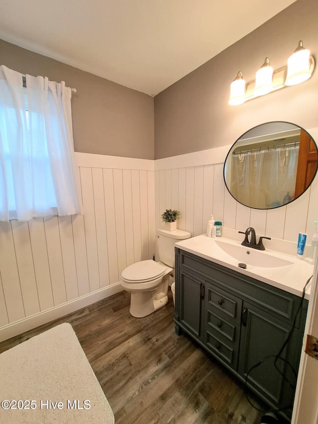 full bath with a wainscoted wall, toilet, vanity, and wood finished floors