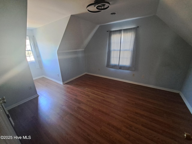 additional living space with baseboards, wood finished floors, and vaulted ceiling