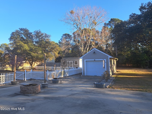 detached garage with concrete driveway and fence