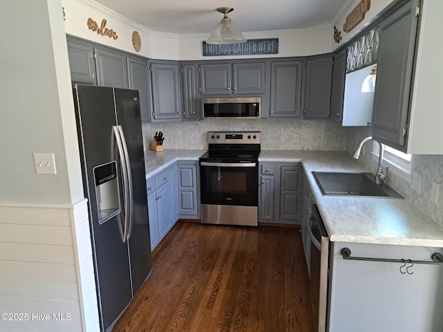 kitchen featuring ornamental molding, a sink, appliances with stainless steel finishes, light countertops, and dark wood-style flooring