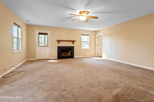 unfurnished living room with baseboards, a ceiling fan, a fireplace, and carpet flooring