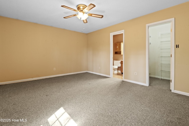 unfurnished bedroom featuring a walk in closet, baseboards, carpet floors, a closet, and ensuite bath