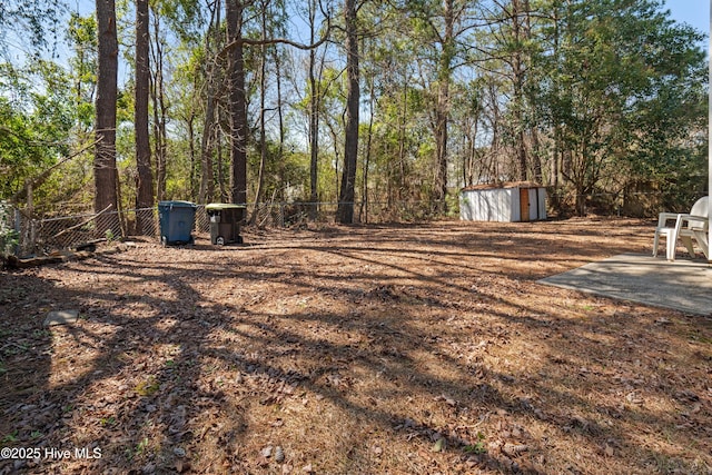 view of yard featuring a storage shed, an outdoor structure, and fence