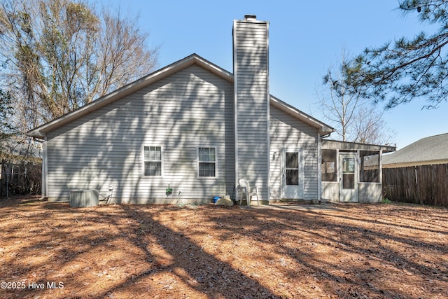 back of house featuring fence, a chimney, and a sunroom