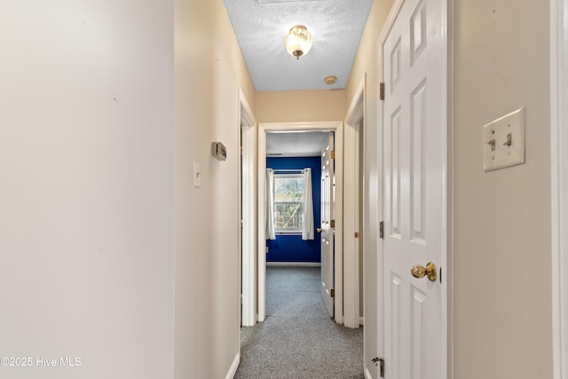 hall with carpet, baseboards, and a textured ceiling