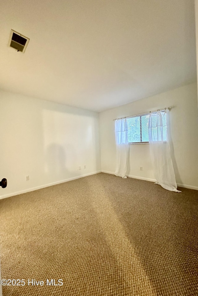 spare room featuring visible vents, baseboards, and dark colored carpet