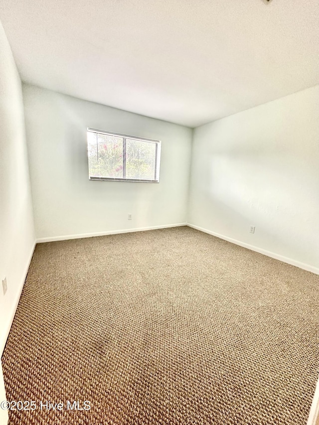 carpeted empty room featuring baseboards