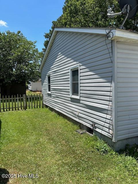 view of side of home featuring a lawn and fence