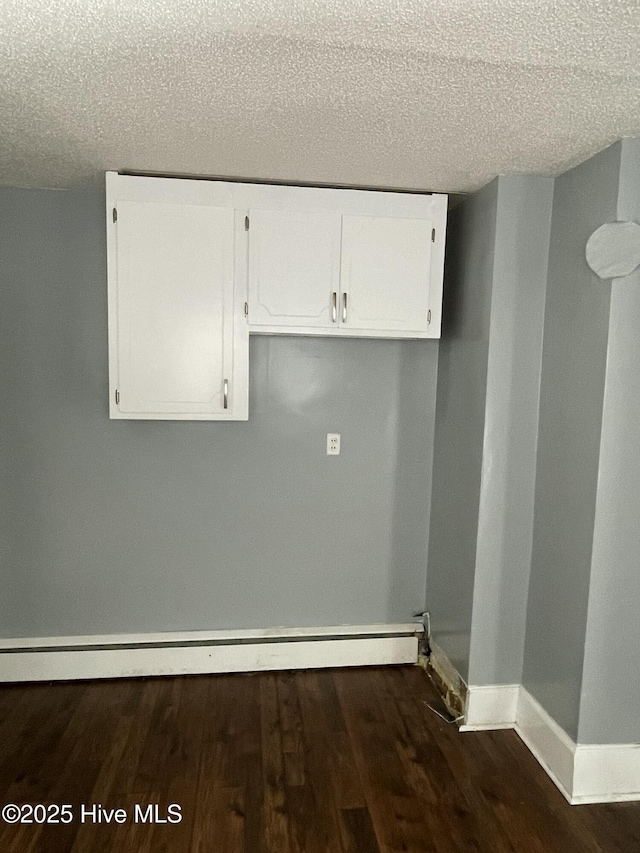 washroom featuring a baseboard radiator, baseboards, dark wood-type flooring, and a textured ceiling