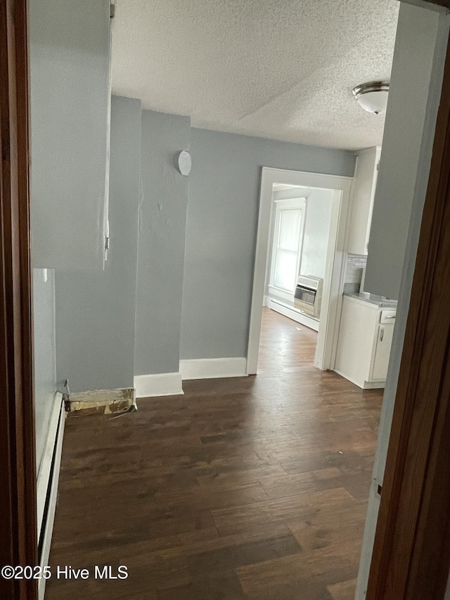 unfurnished room with dark wood-type flooring, baseboards, baseboard heating, and a textured ceiling