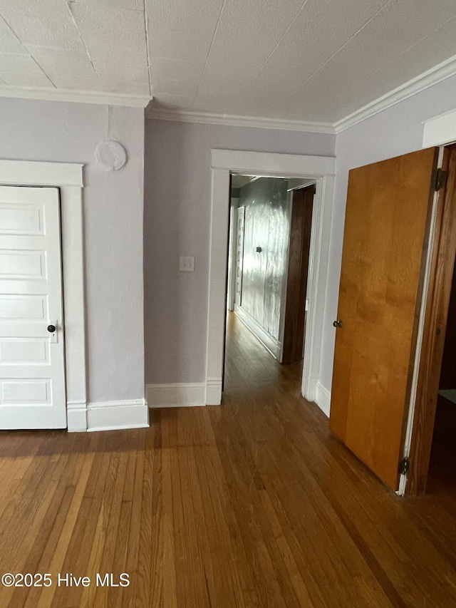 unfurnished room with wood finished floors, baseboards, and ornamental molding