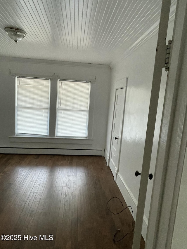 spare room featuring baseboard heating, wood ceiling, ornamental molding, and hardwood / wood-style flooring