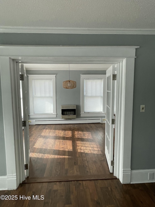 corridor featuring plenty of natural light, heating unit, a textured ceiling, wood finished floors, and crown molding