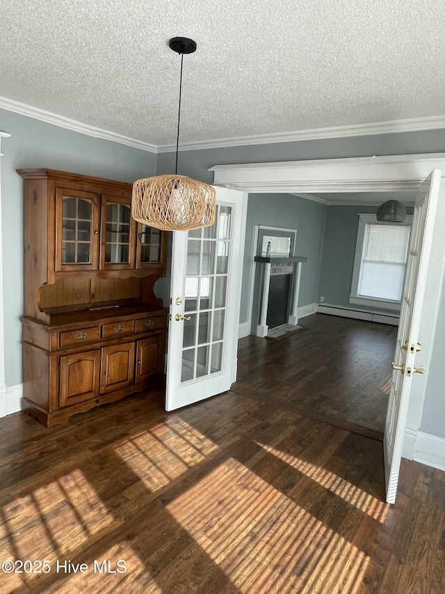 unfurnished dining area featuring a baseboard radiator, a textured ceiling, dark wood-style flooring, and crown molding