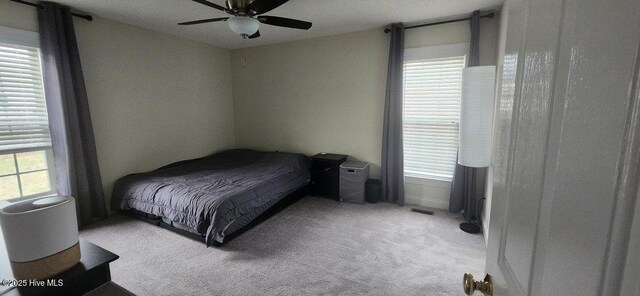 carpeted bedroom featuring multiple windows and a ceiling fan