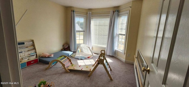 recreation room with a healthy amount of sunlight, a textured ceiling, and carpet