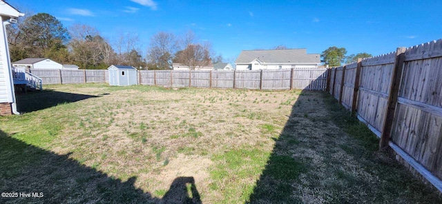 view of yard featuring a storage shed, an outbuilding, and a fenced backyard