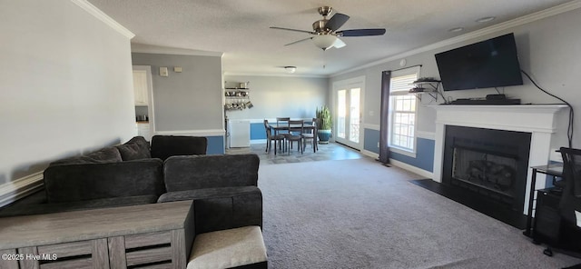 living room with carpet flooring, ceiling fan, crown molding, and a fireplace with flush hearth