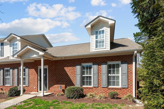 view of front of home featuring brick siding and a shingled roof