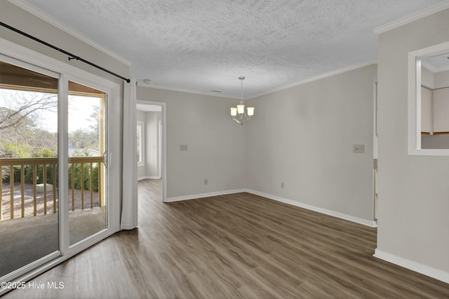 spare room with baseboards, a notable chandelier, wood finished floors, and crown molding