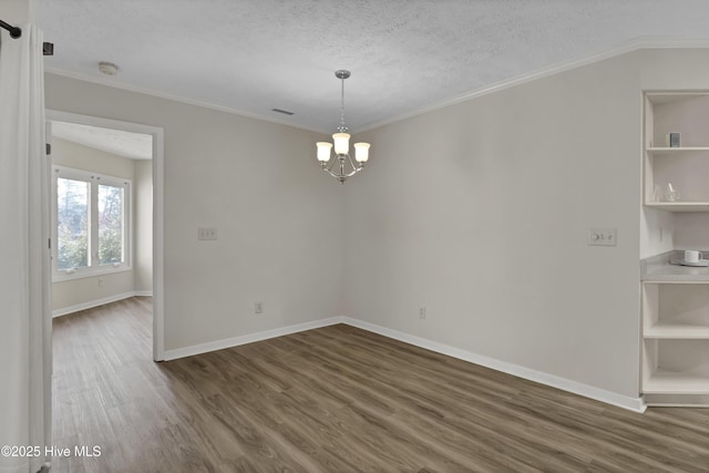 empty room featuring dark wood finished floors, a textured ceiling, crown molding, and an inviting chandelier