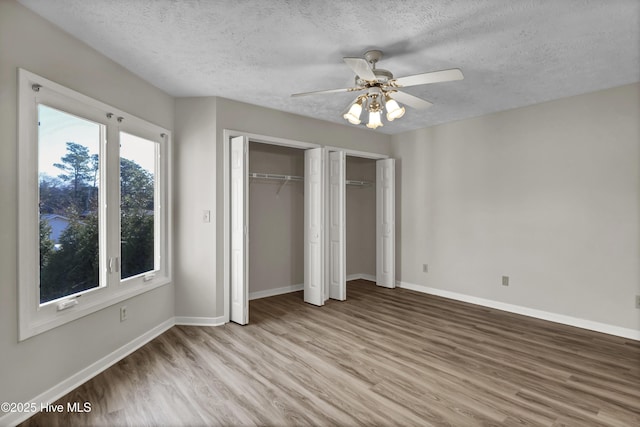 unfurnished bedroom with baseboards, two closets, and light wood-style flooring