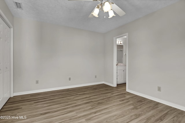 interior space with wood finished floors, baseboards, visible vents, ceiling fan, and a textured ceiling