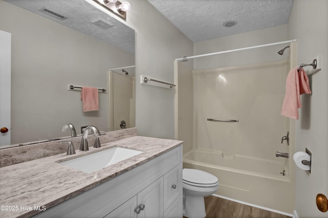 bathroom with wood finished floors, visible vents,  shower combination, a textured ceiling, and toilet