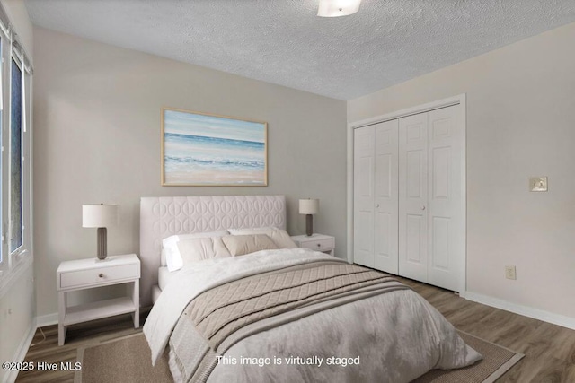 bedroom featuring a closet, baseboards, a textured ceiling, and wood finished floors