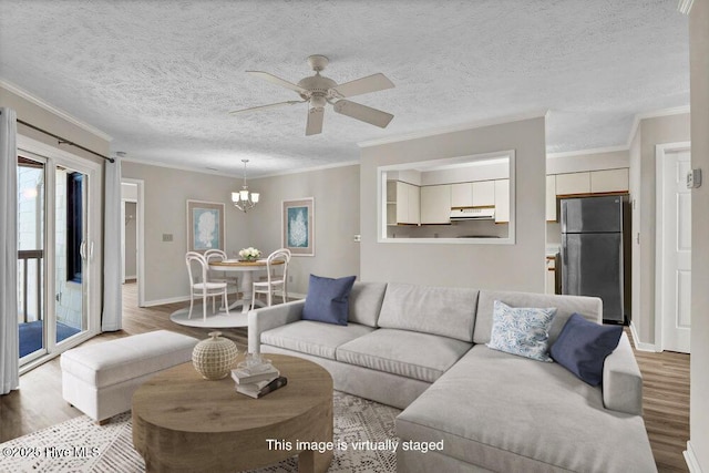 living room featuring ceiling fan with notable chandelier, crown molding, and wood finished floors