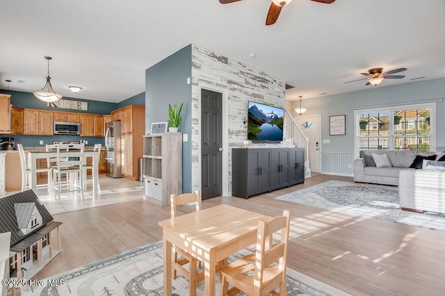 living room with stairway, a ceiling fan, and light wood-style floors