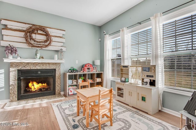 playroom with a fireplace, light wood-type flooring, baseboards, and a sink