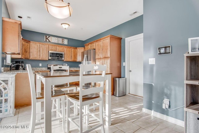 kitchen with light tile patterned flooring, visible vents, appliances with stainless steel finishes, and baseboards