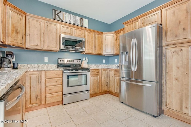 kitchen featuring light tile patterned floors, stainless steel appliances, light stone countertops, and light brown cabinets