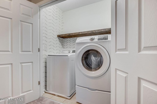 clothes washing area featuring washer and dryer, laundry area, light tile patterned floors, and visible vents