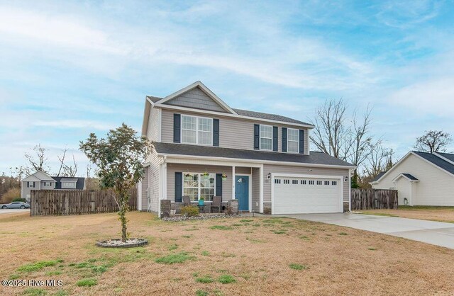 traditional home with fence, concrete driveway, a front yard, covered porch, and an attached garage