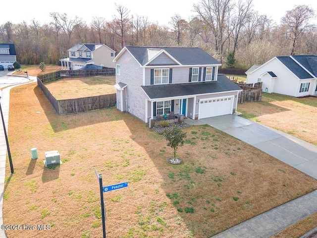 traditional home with covered porch, concrete driveway, a front yard, and fence