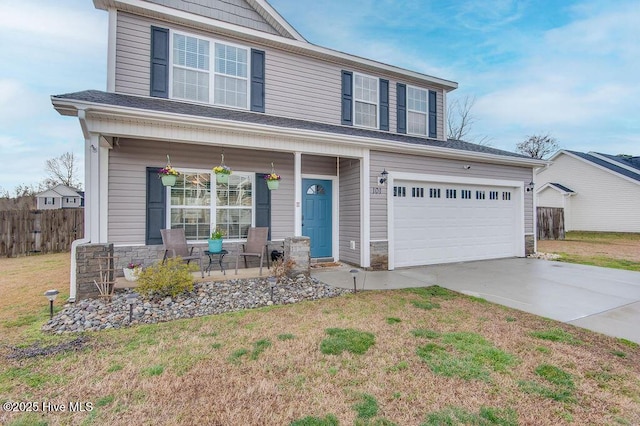 view of front facade with a front yard, fence, covered porch, concrete driveway, and stone siding