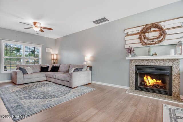 living area with visible vents, a fireplace, baseboards, and wood finished floors