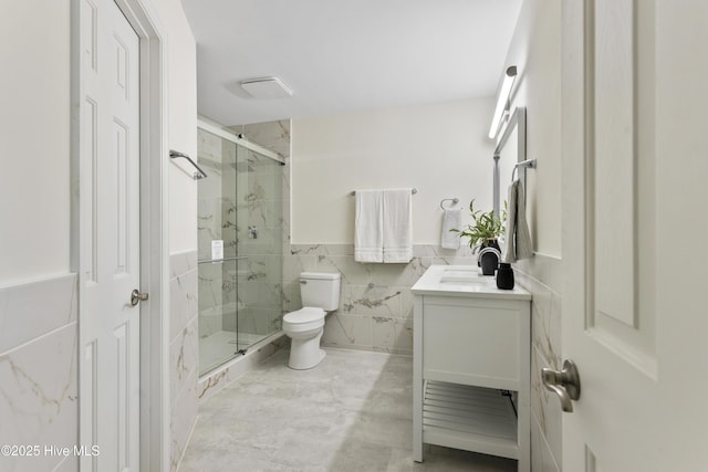 full bathroom featuring a marble finish shower, toilet, tile walls, and vanity