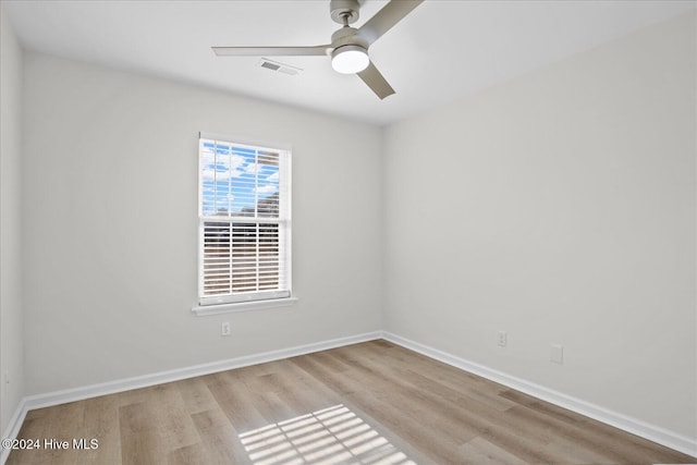 empty room featuring ceiling fan, wood finished floors, visible vents, and baseboards