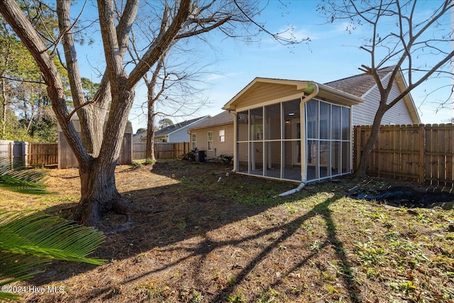 rear view of property with a fenced backyard and a sunroom