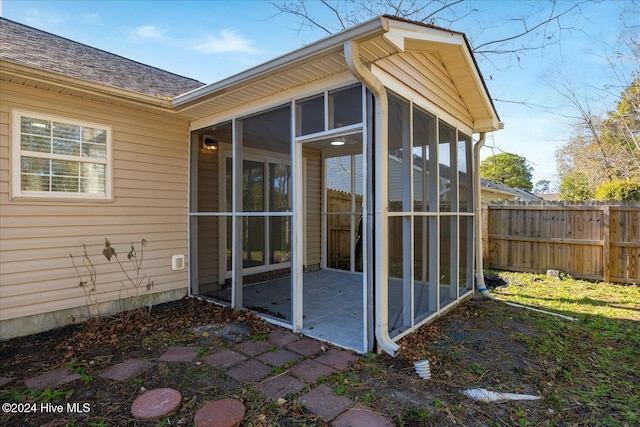 exterior space featuring a patio area, fence, a sunroom, and a shingled roof