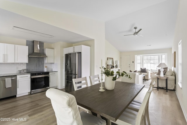 dining area featuring lofted ceiling, wood finished floors, and a ceiling fan